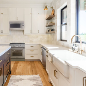 “Modern luxury kitchen with white cabinets, marble waterfall island, pendant lights, and stainless steel appliances.”